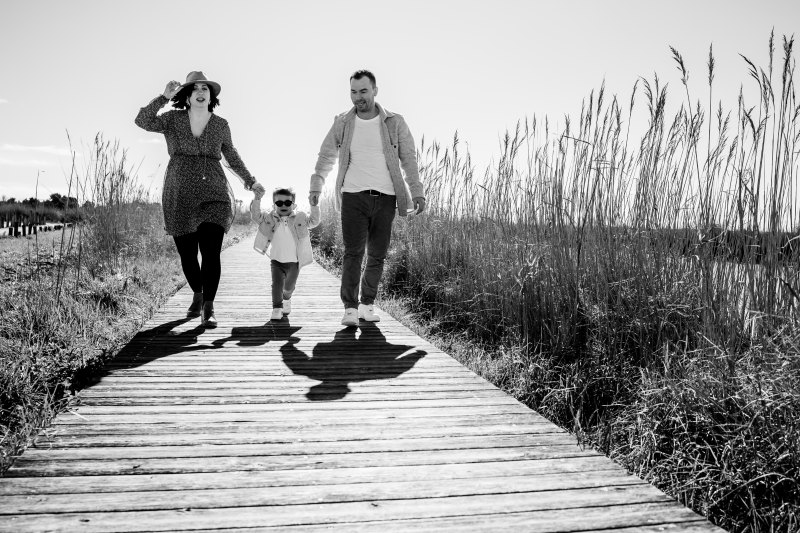 Une famille rit ensemble pendant une séance photo grossesse à Aigues-Mortes, avec un enfant perché sur les épaules de son père