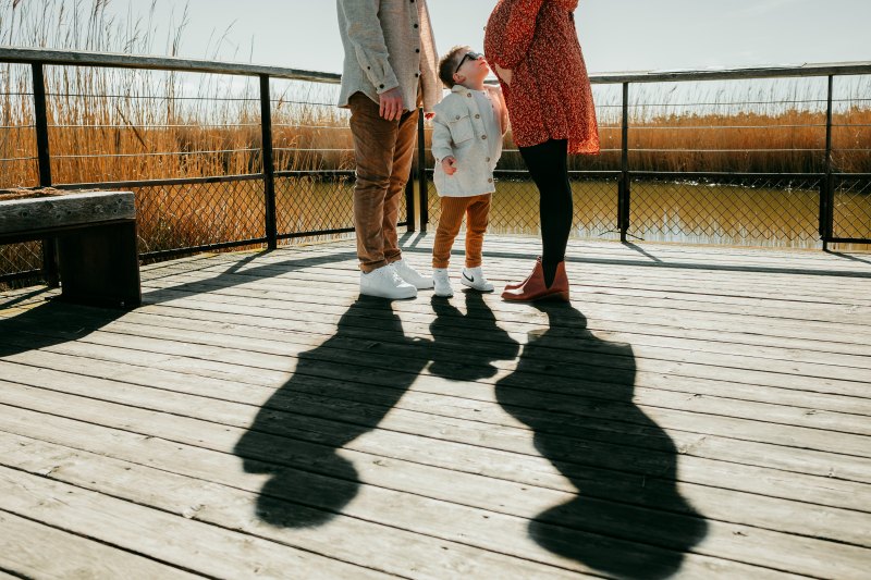 Séance photo grossesse en famille à Aigues-Mortes avec un jeu d'ombres artistiques et Nathan regardant le ventre de sa maman
