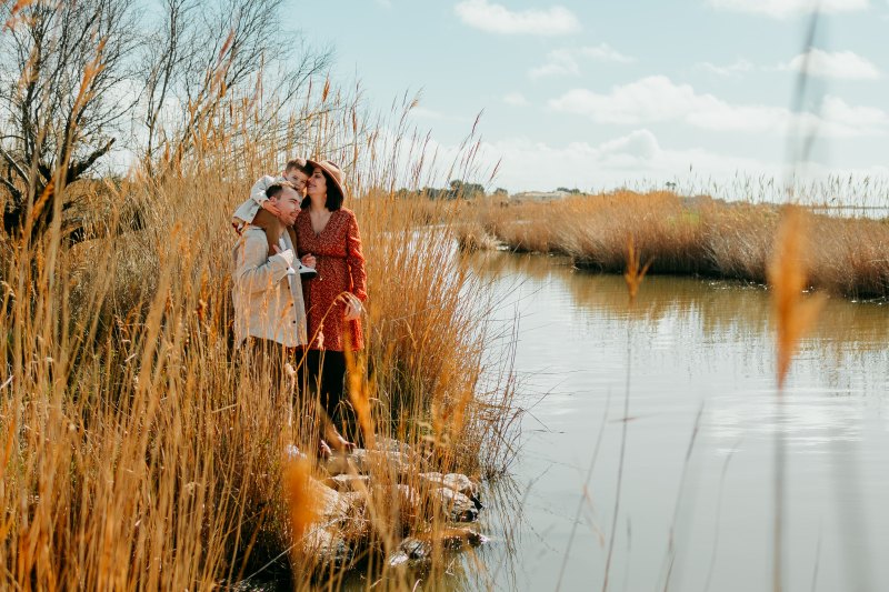 Un couple assiste à un enfant et partage un moment complice sous la lumière dorée d'Aigues-Mortes