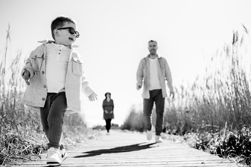 Un enfant court joyeusement devant son père lors d'une séance photo famille à Aigues-Mortes